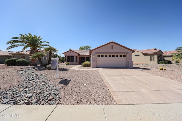 view of front of house featuring a garage, concrete driveway, a tiled roof, and stucco siding