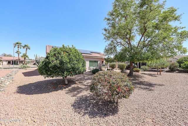 view of front of property featuring stucco siding, a tile roof, and solar panels