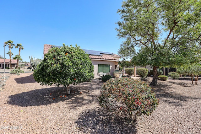 view of front facade featuring solar panels, a tile roof, and stucco siding