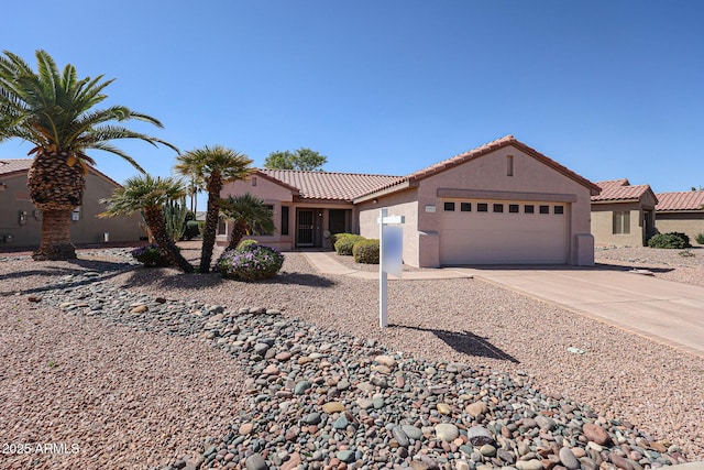 view of front facade with a tile roof, driveway, an attached garage, and stucco siding