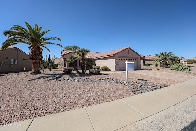 view of front of house featuring an attached garage, a tile roof, concrete driveway, and stucco siding