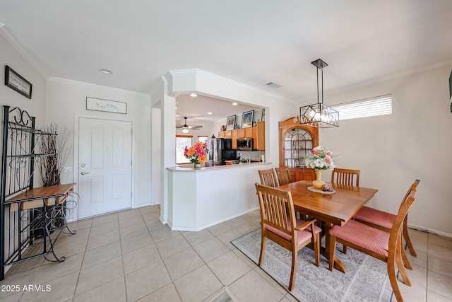 dining room with light tile patterned floors, a healthy amount of sunlight, visible vents, and crown molding