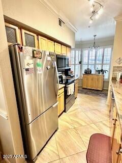 kitchen with rail lighting, light brown cabinetry, decorative light fixtures, ornamental molding, and appliances with stainless steel finishes