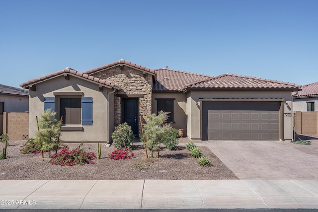 mediterranean / spanish house featuring decorative driveway, a garage, stone siding, and stucco siding