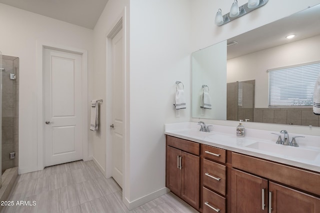 bathroom featuring a tile shower, double vanity, and a sink