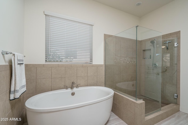 full bath featuring wainscoting, a stall shower, tile walls, and a freestanding tub