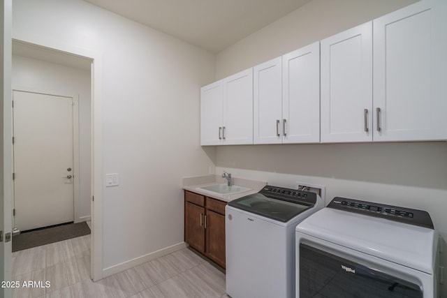 laundry room featuring washing machine and clothes dryer, cabinet space, baseboards, and a sink
