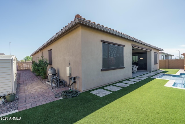 rear view of property with stucco siding, a lawn, a fenced backyard, and a patio area