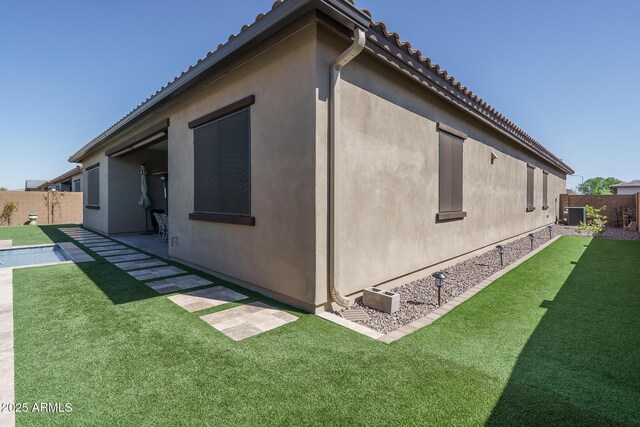 view of property exterior featuring a yard, stucco siding, and a fenced backyard