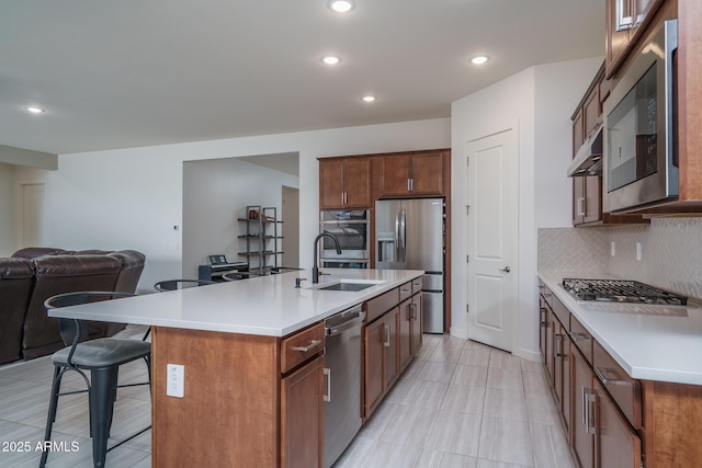 kitchen featuring a breakfast bar, a sink, decorative backsplash, appliances with stainless steel finishes, and open floor plan