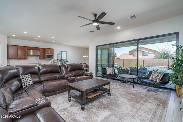 living area with a ceiling fan, recessed lighting, and visible vents