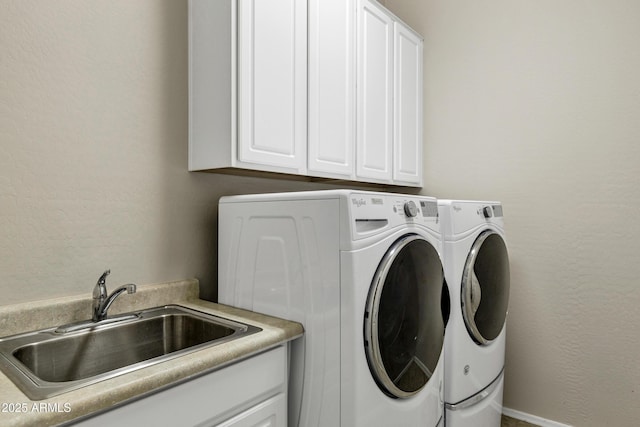 laundry room featuring a sink, a textured wall, washing machine and clothes dryer, and cabinet space