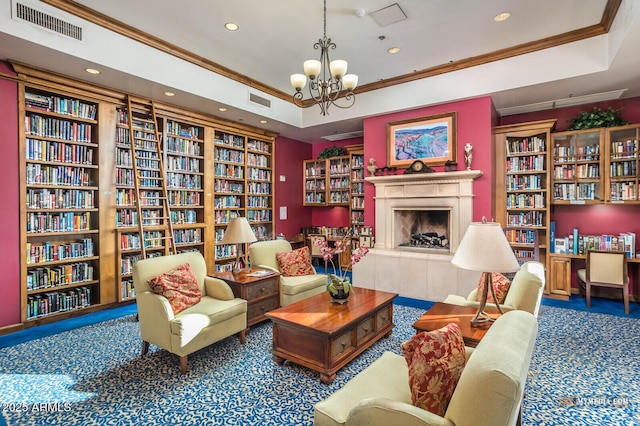 living area featuring wall of books, visible vents, and a tiled fireplace