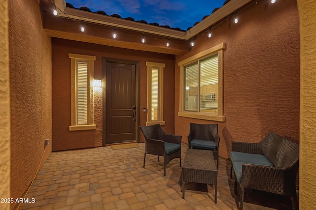 exterior entry at dusk with a patio and stucco siding