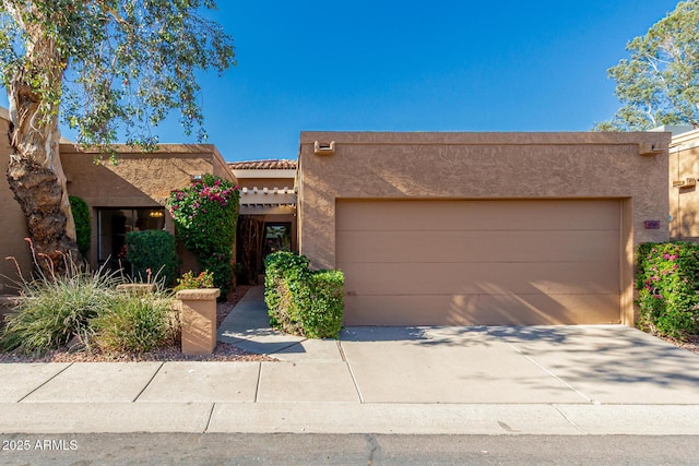 southwest-style home featuring concrete driveway, stucco siding, an attached garage, and a tile roof