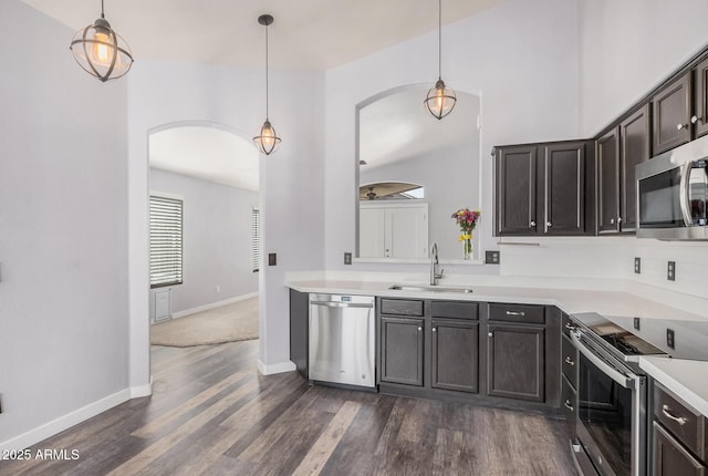 kitchen with a sink, appliances with stainless steel finishes, arched walkways, and light countertops
