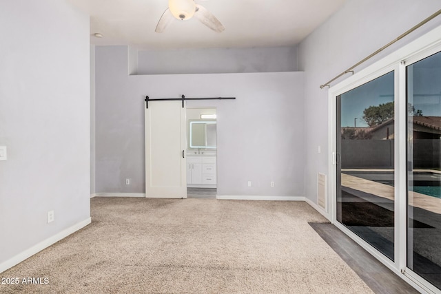 empty room with baseboards, a ceiling fan, carpet flooring, and a barn door