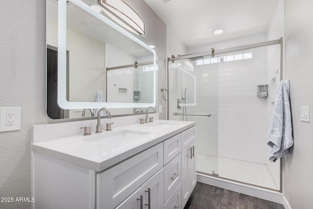 bathroom featuring double vanity, a sink, and a stall shower