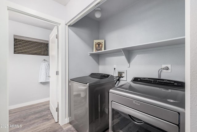 laundry area with laundry area, baseboards, independent washer and dryer, and wood finished floors
