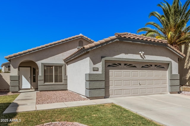 mediterranean / spanish home with a garage, stucco siding, concrete driveway, and a tile roof
