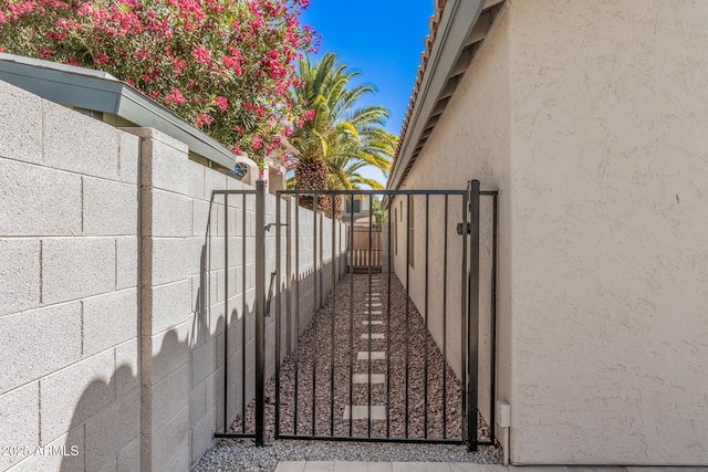 exterior space with a gate, stucco siding, and fence