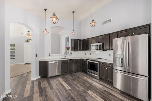 kitchen featuring visible vents, appliances with stainless steel finishes, arched walkways, a sink, and light countertops