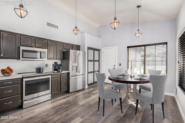 kitchen featuring dark brown cabinetry, high vaulted ceiling, stainless steel appliances, tasteful backsplash, and visible vents