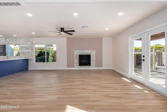 unfurnished living room with a fireplace, ceiling fan, light hardwood / wood-style floors, and sink