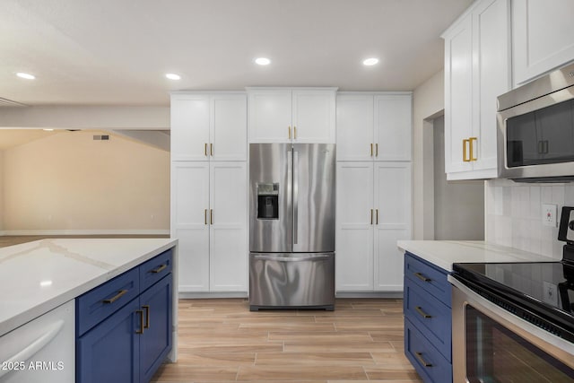 kitchen featuring blue cabinetry, light stone counters, white cabinetry, and appliances with stainless steel finishes