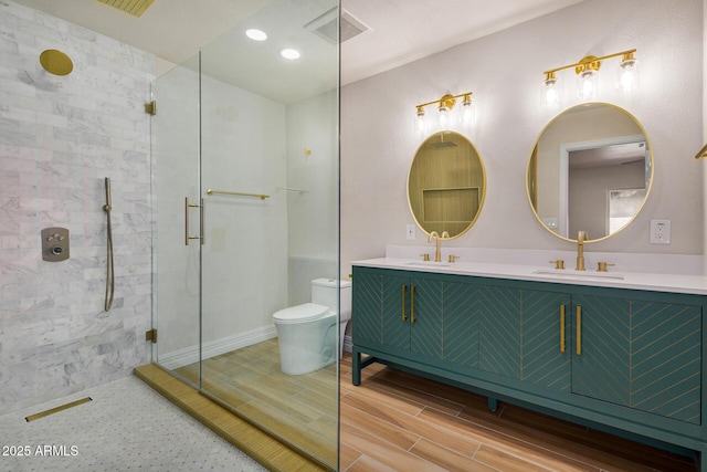 bathroom featuring toilet, vanity, and a shower with shower door