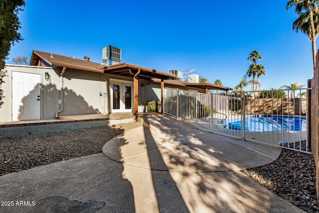 back of property with a patio, french doors, central AC, and a fenced in pool