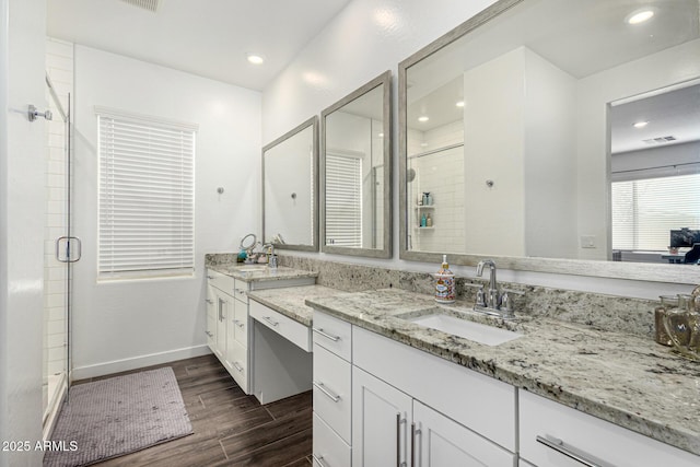 bathroom with visible vents, wood tiled floor, a stall shower, baseboards, and vanity