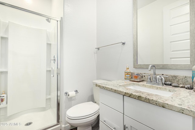 bathroom featuring vanity, a shower stall, and toilet