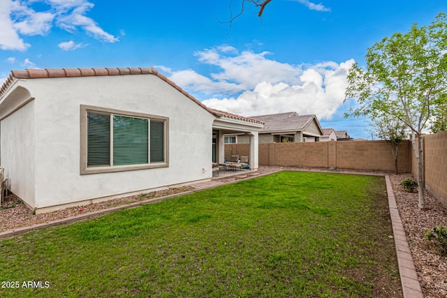 rear view of house featuring a lawn, a patio, a fenced backyard, and stucco siding