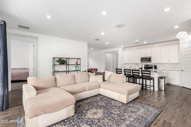 living area with recessed lighting, visible vents, and dark wood-style floors