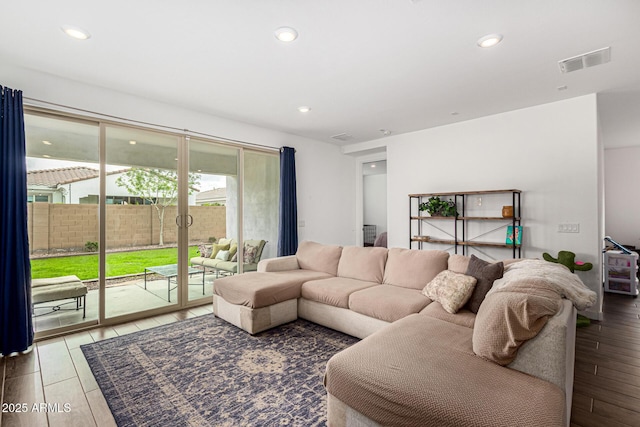 living room with recessed lighting, visible vents, and wood finished floors