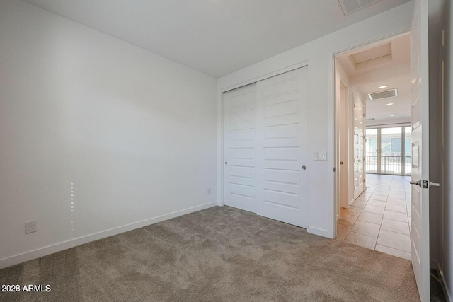 unfurnished bedroom featuring light colored carpet and a closet