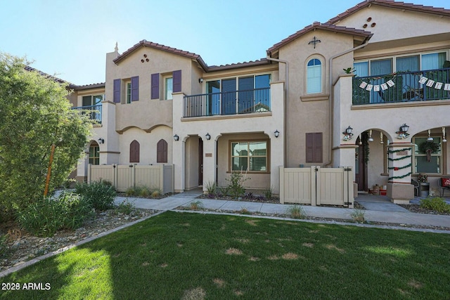 mediterranean / spanish-style home featuring a front lawn and a balcony