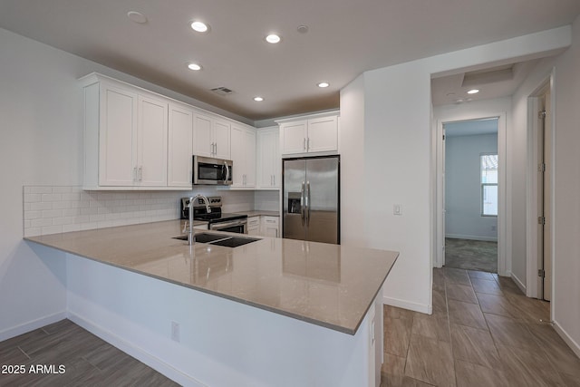 kitchen with stainless steel appliances, tasteful backsplash, white cabinets, and kitchen peninsula