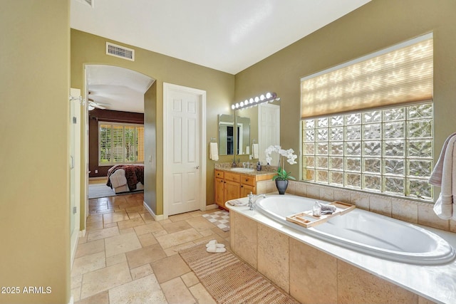 3531 E Norwood Cir, Mesa, AZ 85213 - ensuite bathroom featuring vanity, a garden tub, baseboards, stone tile floors, and a ceiling fan