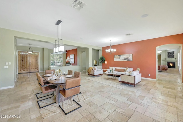 3531 E Norwood Cir, Mesa, AZ 85213 - dining room with stone tile flooring, baseboards, arched walkways, a chandelier, and a lit fireplace