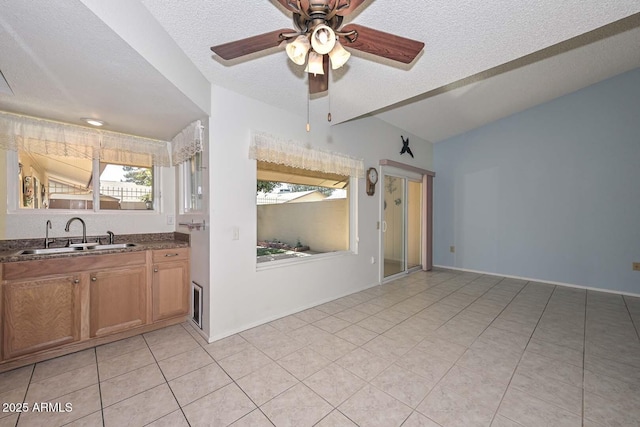 kitchen with dark countertops, light tile patterned floors, brown cabinets, and a sink