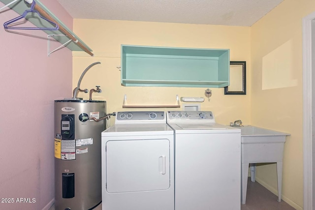 laundry room with a textured ceiling, electric water heater, laundry area, baseboards, and independent washer and dryer