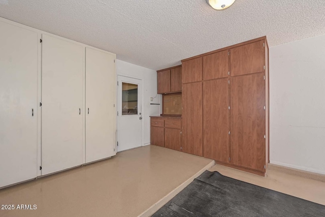 kitchen featuring a textured ceiling, light countertops, and brown cabinets