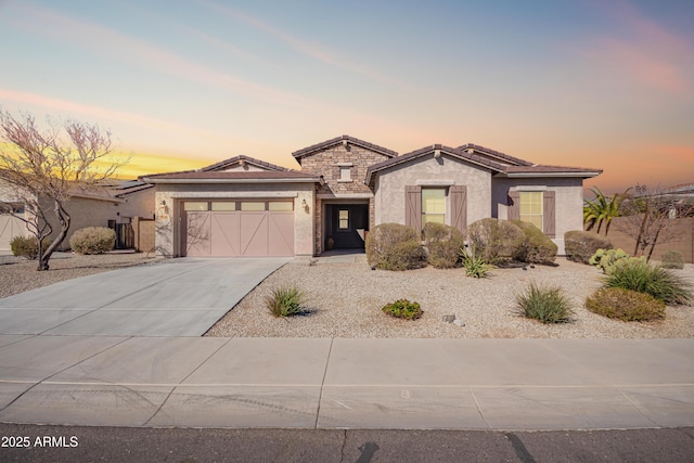 18406 W Verbena Dr, Goodyear, AZ 85338 - view of front of house with driveway, stone siding, a tiled roof, an attached garage, and stucco siding