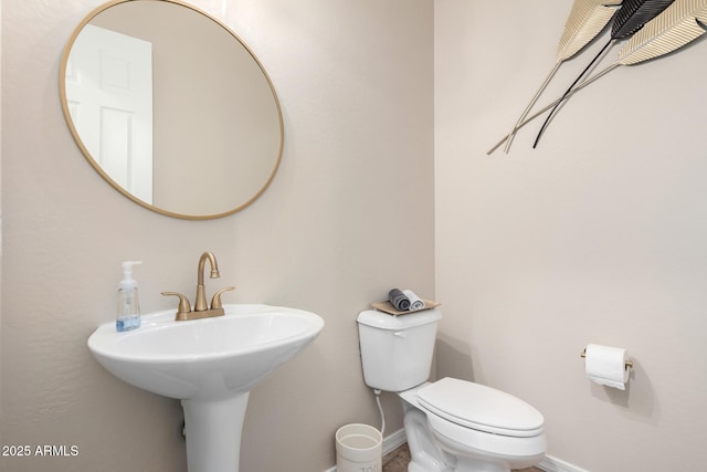 half bathroom featuring toilet, baseboards, and a sink