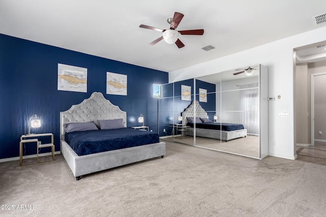 bedroom with visible vents, baseboards, a ceiling fan, an accent wall, and carpet