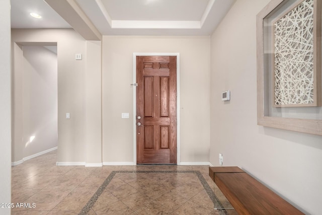 foyer with a raised ceiling and baseboards