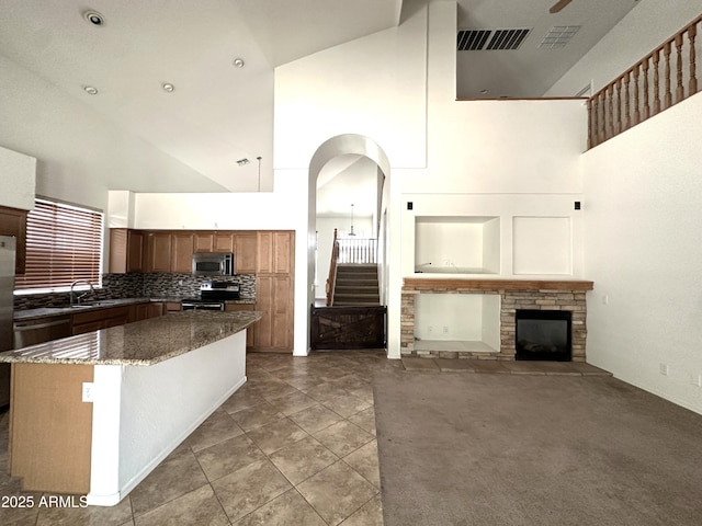 33506 N 24th Dr, Phoenix, AZ 85085 - kitchen featuring high vaulted ceiling, stainless steel appliances, a fireplace, a center island, and dark stone countertops