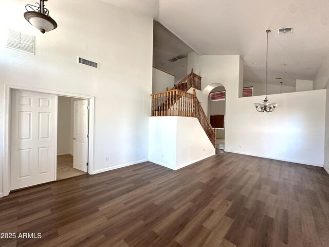 33506 N 24th Dr, Phoenix, AZ 85085 - unfurnished living room with high vaulted ceiling, a chandelier, stairs, dark wood-type flooring, and arched walkways